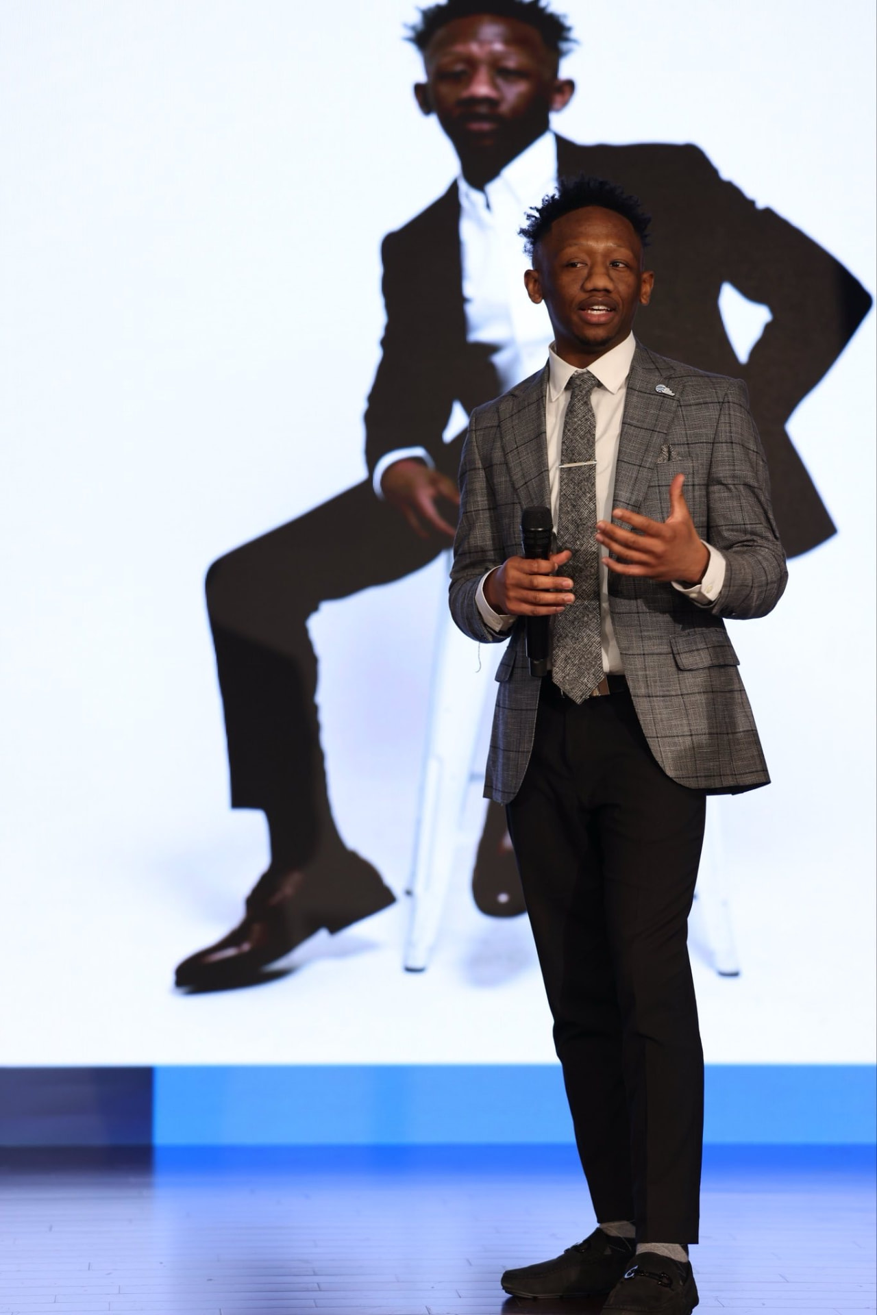 Jaquez X. Baldwin speaking on stage with a microphone
